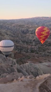 Türkiye 'nin Kapadokya üzerinde gökyüzünde uçan sıcak hava balonlarının dikey videosu.