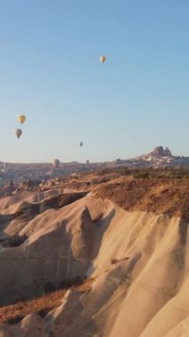 Türkiye 'nin Kapadokya üzerinde gökyüzünde uçan sıcak hava balonlarının dikey videosu.