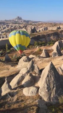 Türkiye 'nin Kapadokya üzerinde gökyüzünde uçan sıcak hava balonlarının dikey videosu.