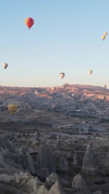 Türkiye 'nin Kapadokya üzerinde gökyüzünde uçan sıcak hava balonlarının dikey videosu.