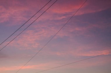 Gün batımında gökyüzü kırmızı bulutlar ve elektrik kablolarıyla. Endüstri ve doğa.