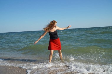 Kız sahilde dalgalarla oynuyor.