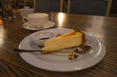 Tabakta cheesecake ve restoranda bir fincan çay..