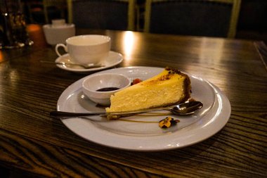 Tabakta cheesecake ve restoranda bir fincan çay..