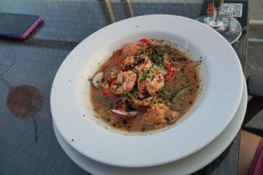 Büyük kaplan karidesli salata ve beyaz porselen tabakta sos..