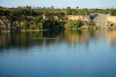 İnsanlar granit kanyonun sakin sularında kayıklarla yüzerler.