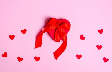 Kurdeleli kırmızı hediye kutusu ve pembe arka planda bir kupa deseni. Aşk konsepti, kopyalama alanı, düz yatış, metin, pankart, üst görünüm.