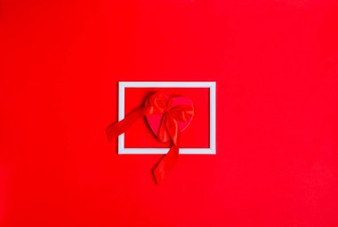 Kırmızı arka planda beyaz çerçeveli bir kalp şeklinde bir hediye kutusu. Aşk konsepti, kopyalama alanı, düz yatış, metin, pankart, üst görünüm.