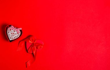 Kırmızı arka planda beyaz kalpli bir kurdeleyle hediye kutusu. Aşk konsepti, kopyalama alanı, düz yatış, metin, pankart, üst görünüm.