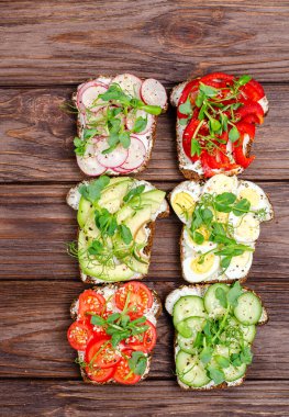 Sebzeli farklı sandviçler ve ahşap arka planda kızarmış ekmek. Düz yat, sağlıklı çerez. Yukarıdan bak. Dikey yönelim