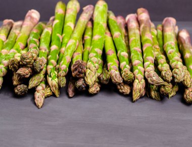 Siyah arka planda taze yeşil kuşkonmaz. Mevsimlik bahar hasadı. Düz konum, kopyalama alanı. Sağlıklı gıda konsepti. Yakın plan.