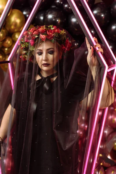 Una mujer adulta con un disfraz de bruja en el fondo de un ataúd de neón. Retrato de Halloween — Foto de Stock