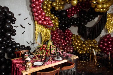 Cadılar bayramı için servis edilen boş güzel masa. Tabaklar, kafatasları, örümcekler ve dalların yanında mor topların arka planına karşı.
