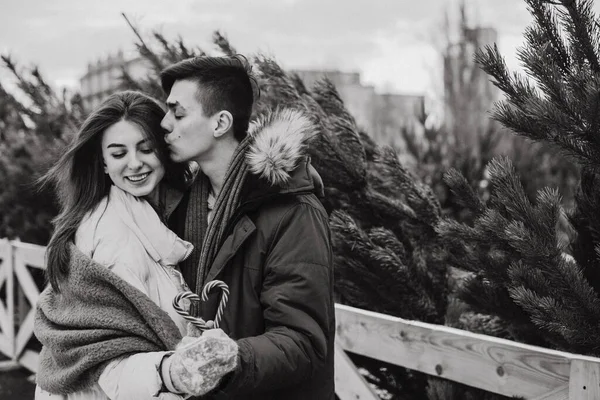 Ένα νεαρό ζευγάρι κρατάει ένα ζαχαροκάλαμο σε σχήμα καρδιάς και αγκαλιάζει. Το πορτραίτο των εραστών. Χριστούγεννα, νέο έτος και αγάπη έννοια. Εξωτερική — Φωτογραφία Αρχείου