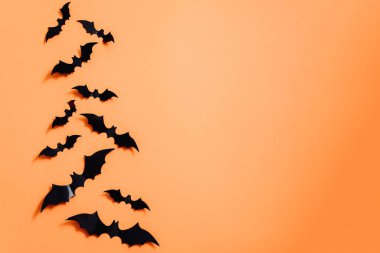 Turuncu arka planda suni yarasalar. Cadılar Bayramı konsepti Düz konum, üst görünüm, kopyalama alanı