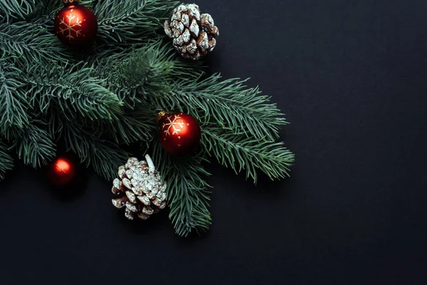 Vánoční strom větev s červenými vánoční koule na černém pozadí. Vánoční přání s mezerou. Byt ležel, horní pohled — Stock fotografie