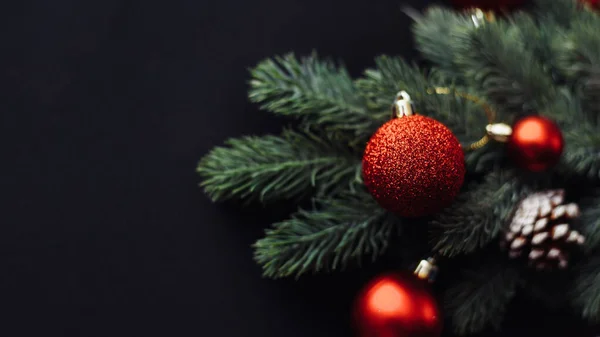 Червоні різдвяні кульки на гілці ялинки на чорному тлі. Шаблон вітальних листівок, макет веб-банера. Плоский простір, вид зверху, простір для копіювання — стокове фото