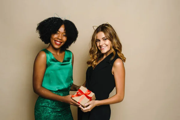 Dos jóvenes felices de diferentes nacionalidades están celebrando una Navidad y Año Nuevo presentes en un fondo beige — Foto de Stock