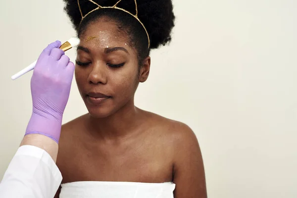 Spa schoonheidsbehandeling, huidverzorging. Een vrouw die gezichtsverzorging krijgt van een schoonheidsspecialiste. Jonge cosmetoloog aanbrengen gezichtsmasker door borstel in spa — Stockfoto