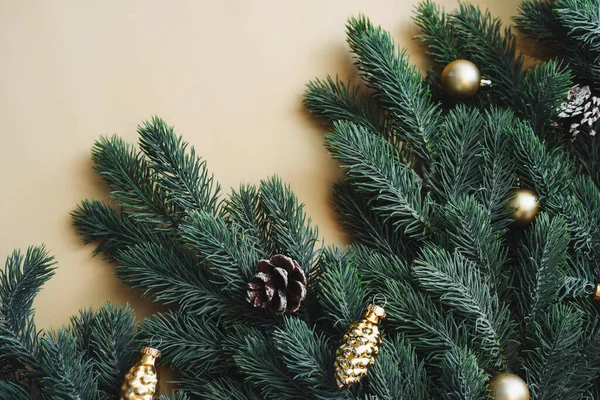 Platz für Text zwischen Weihnachtsbaumzweigen mit weihnachtlichem Goldschmuck und Kugeln auf beigem Hintergrund. Weihnachtskomposition. Frohes neues Jahr. Raum für Text — Stockfoto
