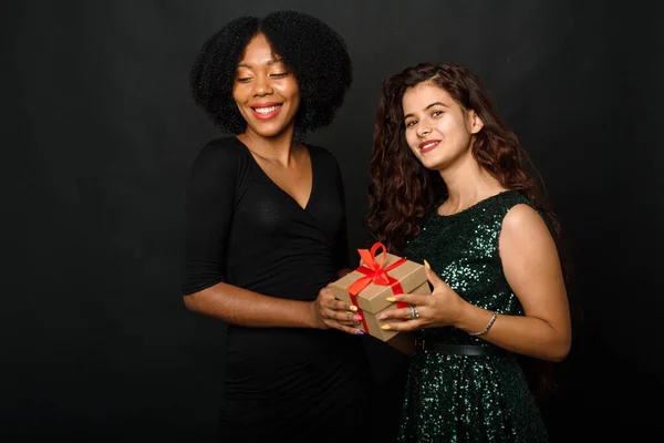 Retrato interior de duas melhores amigas felizes irmãs mulheres, pronto para festa de férias, segurando presentes e presentes brilhantes, vestindo vestidos brilhantes — Fotografia de Stock