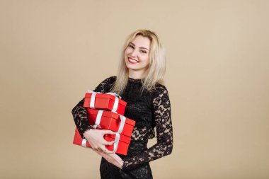 Siyah elbiseli hoş bir genç bayan elinde bir sürü kırmızı hediye tutuyor. Tatil konsepti, hediye vermek.