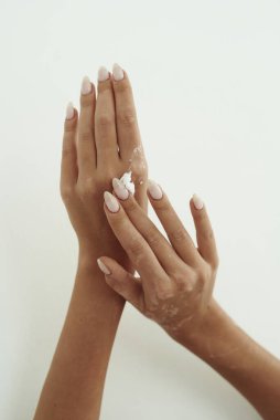 Genç kadın ellerine el kremi dağıtıyor. Cilt hidrasyonu, el bakımı ve kırışıklık önleme kavramı