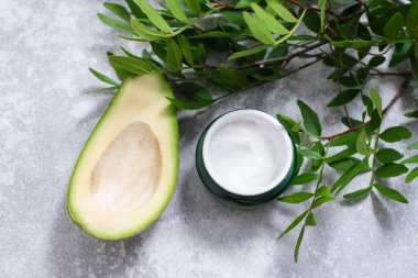Avokado tohumu özlü krema. Avokado ve yaprakların arkasındaki cilt için nemlendirici krem