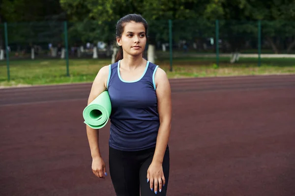 Een mooie vrouw staat op een straat workout site na een intensieve training. Ontspanning na buitensporten — Stockfoto