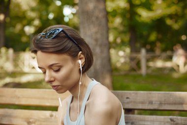 Cep telefonuyla müzik dinleyen genç bir Amerikalı kadının portresi.