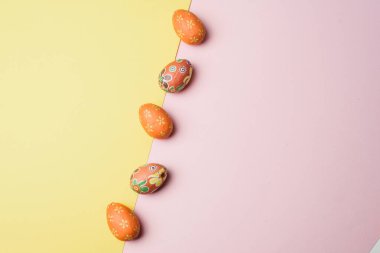 Pembe ve sarı renkli arka planda birçok Paskalya yumurtası. Yumurtalar süslenmiş. Düz yatış stili. Paskalya kartpostalı.