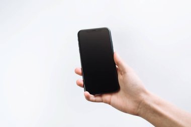 Samara Rusya - 04.05.2020: Genç bir adam akıllı telefona tırmandı. Siyah akıllı telefonu tutan iş adamı. En son Apple iPhone X veya 11, 12