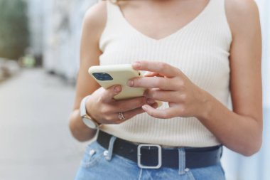 Mutlu, başarılı, gülümseyen bir kadın, açık sokak arka planında online alışveriş yapmak için akıllı telefonu kullanıyor. Kapat.