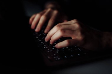 Karanlık operasyon odasında dizüstü bilgisayarda klavyeyi yazan adam elini kapat, siber güvenlik kavramı. Bilgisayar kullanan bir hacker