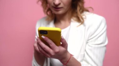 İletişim için sosyal medyayı tarıyorum. Stüdyoda pembe arka planda izole edilmiş. Telefona tırmanan bir kadının yakın plan fotoğrafı.