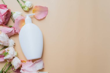 Bej arka planda beyaz tüpler içinde krema ve gül çiçekleri. Cilt bakımı için doğal malzemelerden kozmetik ürün