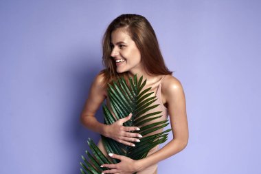 Neşeli, güzel, çekici kadın gülümseme palmiyesi yaprakları. Model arkasında bir avuç yaprağı. Çok güzel. Sağlıklı Sıvı Deri İçin Organik Kozmetik ve SPA Tedavisi