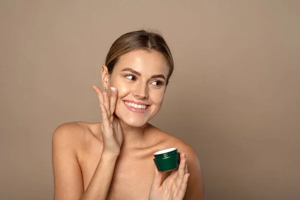 Mujer Joven Aplica Crema Hidratante Cara Sonríe Concepto Cuidado Piel — Foto de Stock