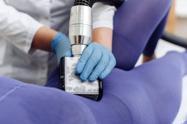 Güzellik uzmanı mor takım elbiseli genç bayana karın ve bel masajı yapıyor. Lenfatik drenaj masajı. Zayıflatıcı tedaviler