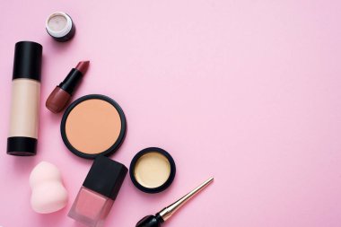 Pembe arka planda dekoratif kozmetik ürünler. Ruj, pudra, göz farı ve parlak makyajın temeli. Kopyalama alanı