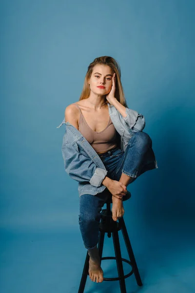 Aantrekkelijke vrouw in casual kleding. Fashionable vrouw-model poseren op de stoel, studio fotografie — Stockfoto