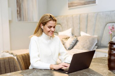 Genç bir kadın evdeki masada oturuyor ve bir dizüstü bilgisayarda çalışıyor. İş kadını Serbest Çalışan