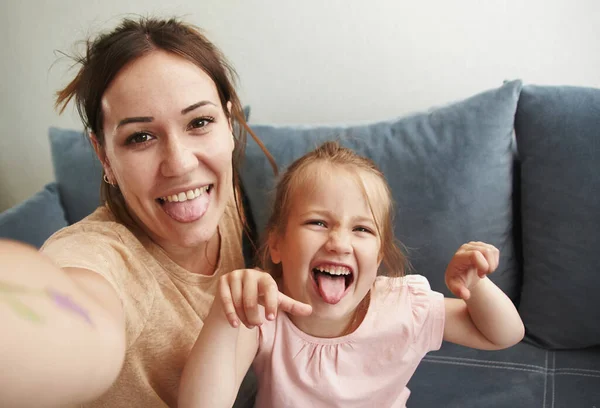 Young mother with her baby daughter take selfies and fool around looking at the camera — Stock Photo, Image