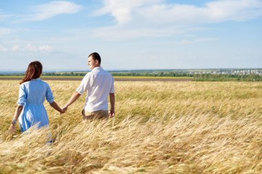 Mutlu çift çayırda el ele yürüyor. Aşk kavramı, iyi ilişkiler, anlayış ve uyum.