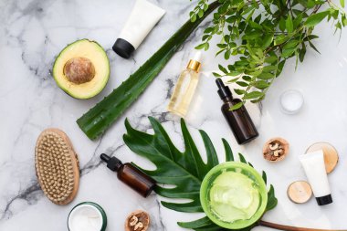 Yağ, aloe, sabun, avokado ve fındıklı güzel bir kompozisyon. Palmiye yaprağı arka planında kaplıca ürünleri olan şişeler. Güzellik salonu prosedürleri konsepti