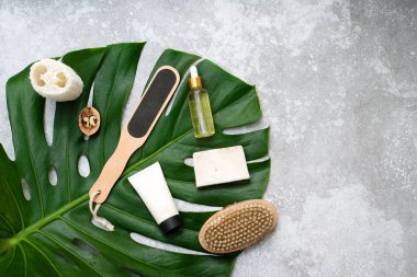 Gri arka planda vücut bakım ürünleri ve bitkilerle spa kompozisyonu. Üst görünüm