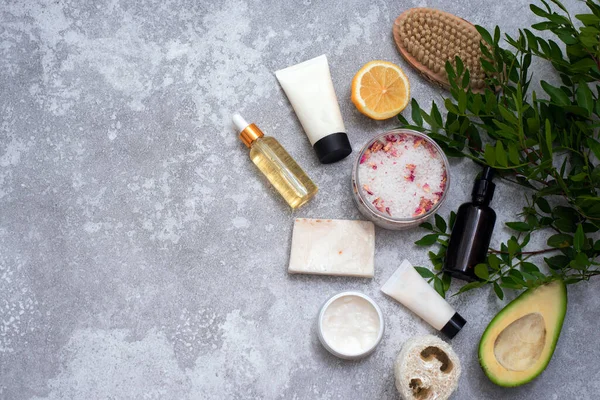 Spa composition with body care items and plants on a gray background. Top view