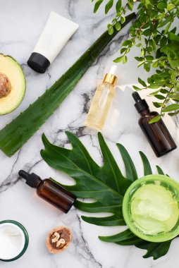 Yağ, sabun, avokado ve fındıklı güzel bir kompozisyon. Palmiye yaprağı arka planında kaplıca ürünleri olan şişeler. Güzellik salonu prosedürleri konsepti