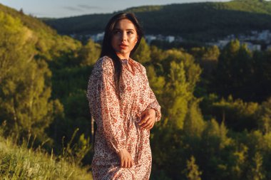 Genç kadın tepenin üstünde. Yeşiller içindeki çekici esmer. Gizemli kadın uzaklara bakıyor.