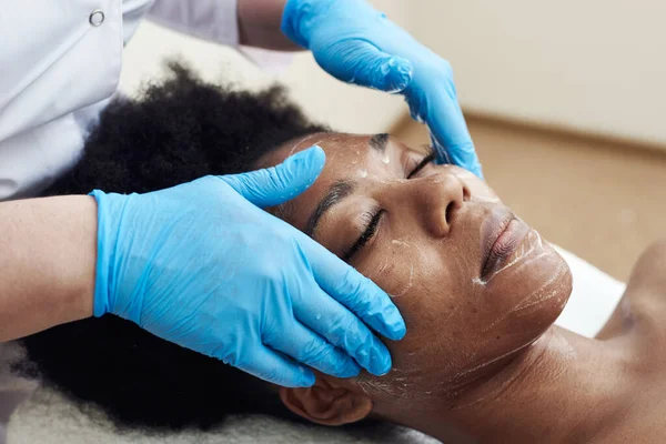 Een jonge zwarte vrouw ligt in het schoonheidssalon en ontspant van zachte aanrakingen en toning massage — Stockfoto